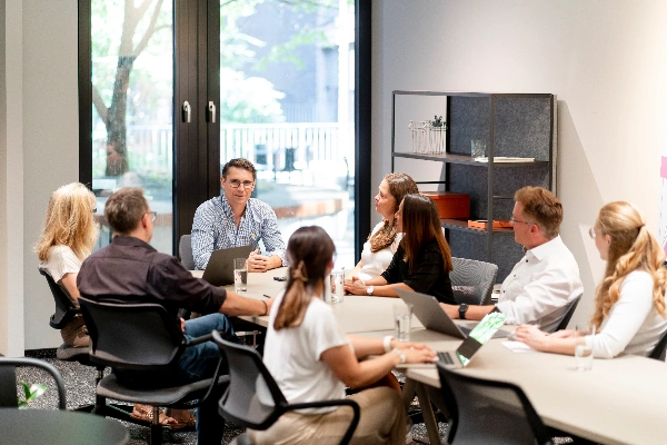 Berater erklärt Strategie am Flipchart vor Team im Meetingraum und vermittelt ganzheitlichen Überblick im Workshop mit 360°-Blick auf Prozesse.
