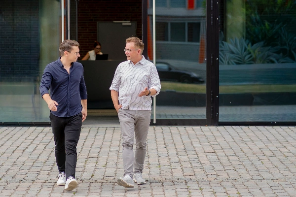Zwei Geschäftsleute diskutieren Strategien und Dokumente am Konferenztisch und entwickeln gemeinsam innovative Individuallösungen für komplexe Herausforderungen.