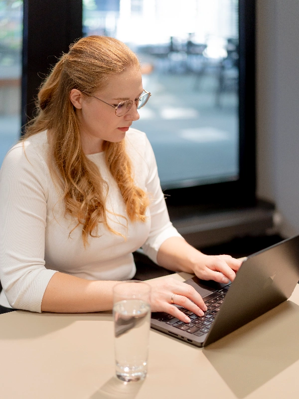 Beraterin spricht mit zwei Kunden am Tisch im modernen Büro und entwickelt gemeinsam individuelle Strategien und passgenaue Individuallösungen.
