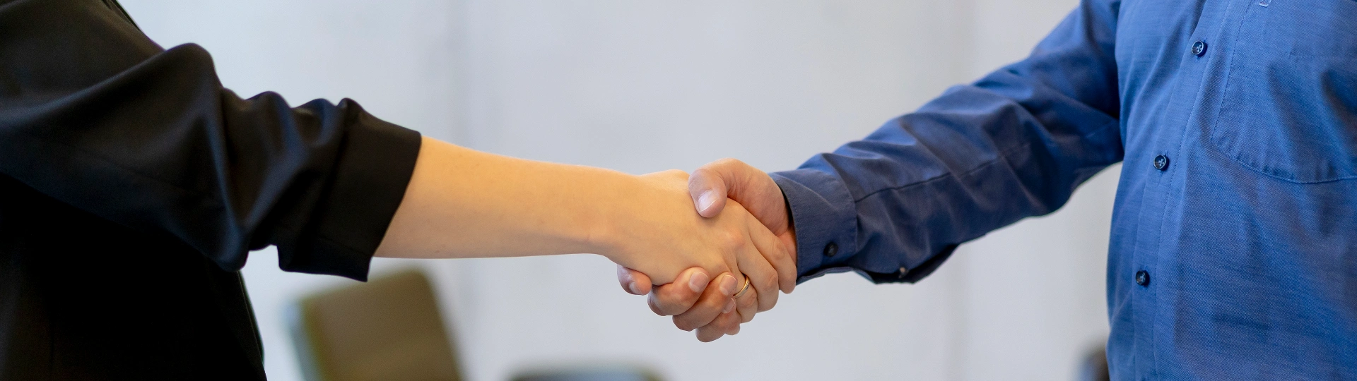 Geschäftspartner schütteln sich die Hand im Meetingraum, während Teammitglieder zusehen, symbolisiert erfolgreiche Zusammenarbeit und Vertrauen bei ProKanzlei.